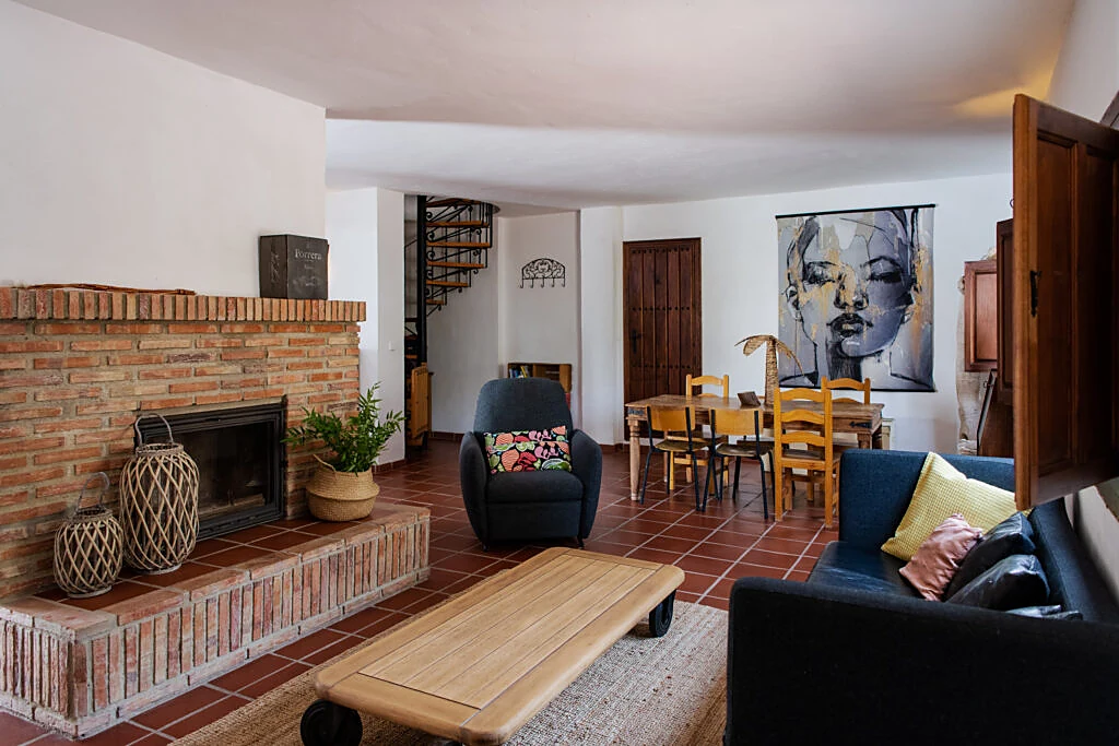 Living room with brick fireplace, armchair and a spiral staircase