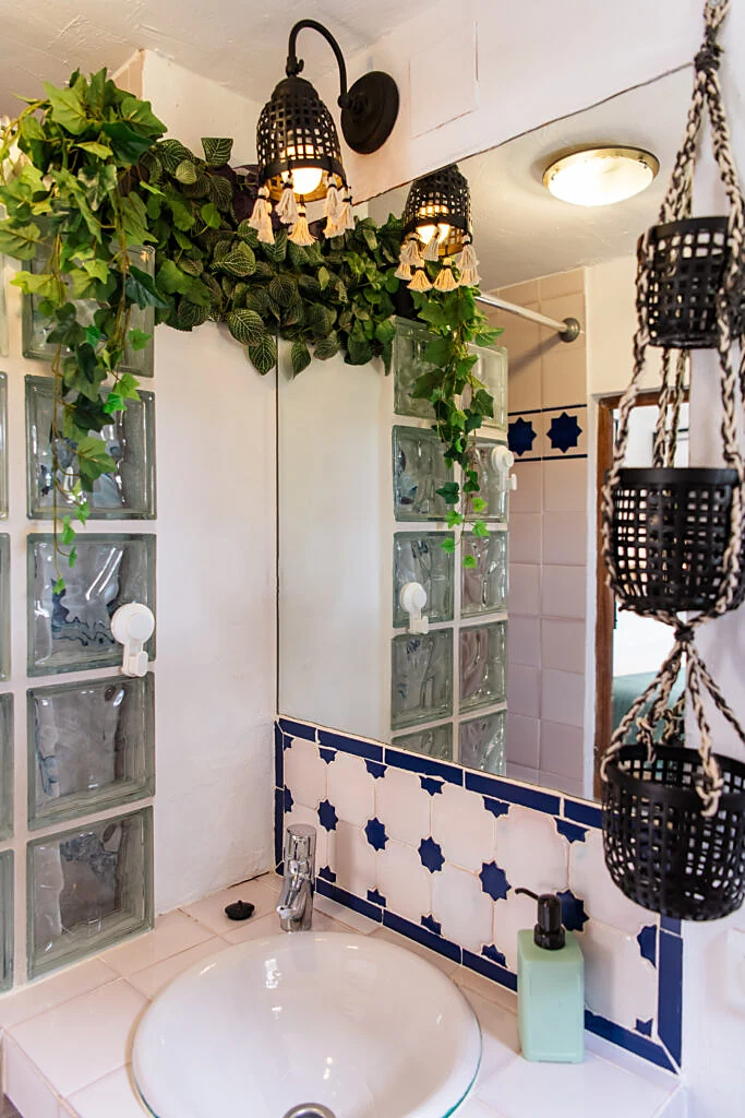 Washbasin with blue Andalusian tiles, trailing plants and lantern lights