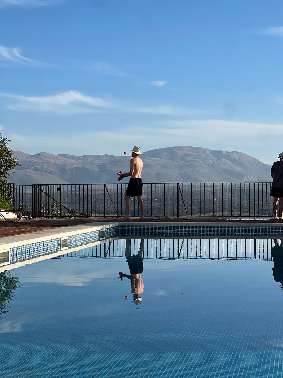 Juggling beside the pool with distant mountains reflected in the water