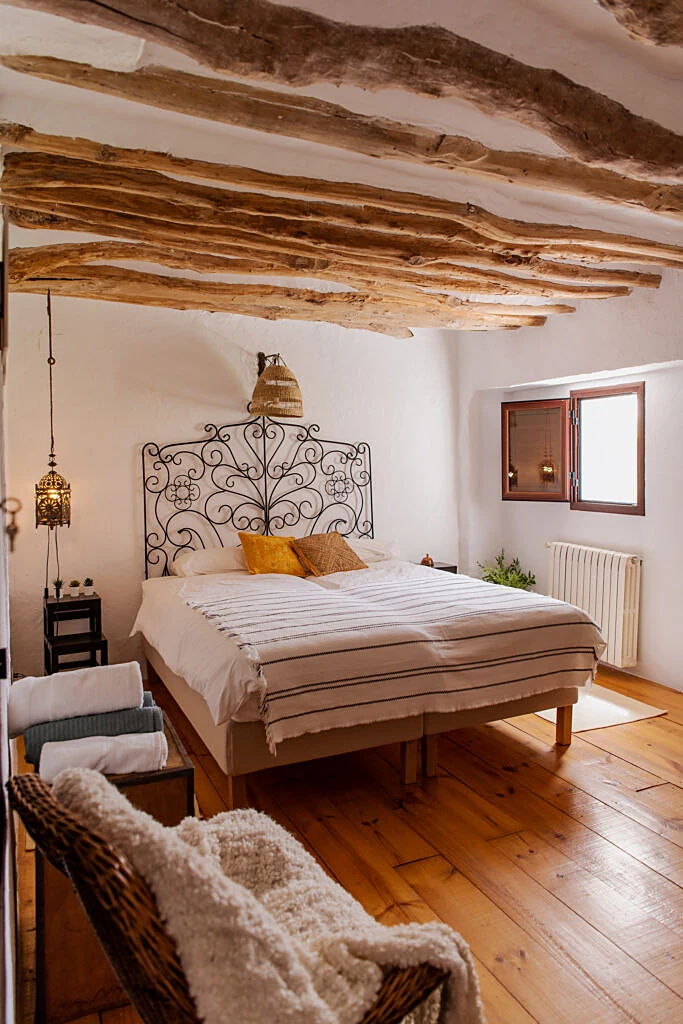 Bedroom with rustic ceiling beams and a wrought-iron headboard
