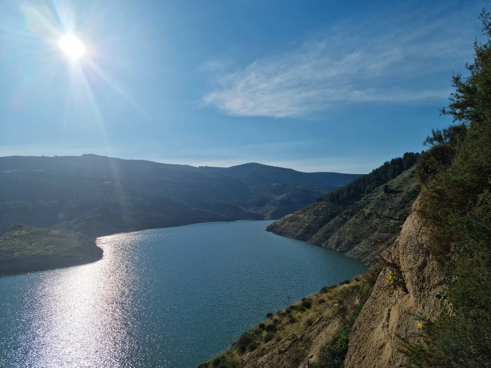 Sunlight sparkling on a reservoir between steep green hills
