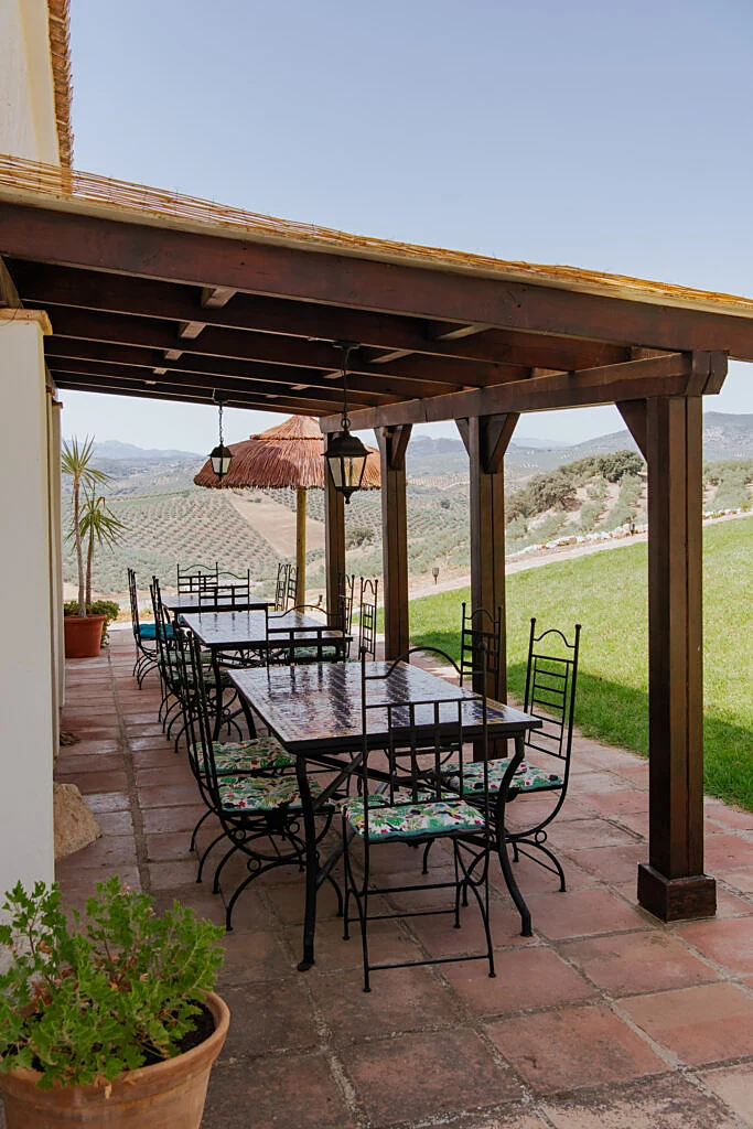 Covered dining pergola with tiled tables overlooking the olive groves