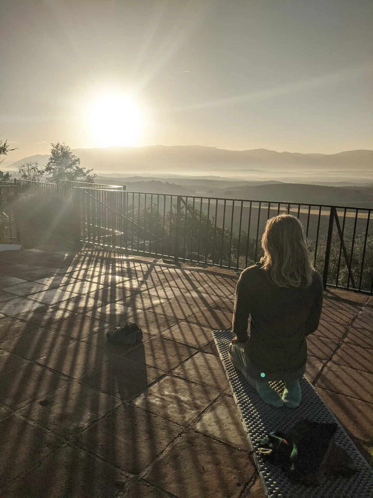 A person sitting quietly on the terrace in the morning sunlight