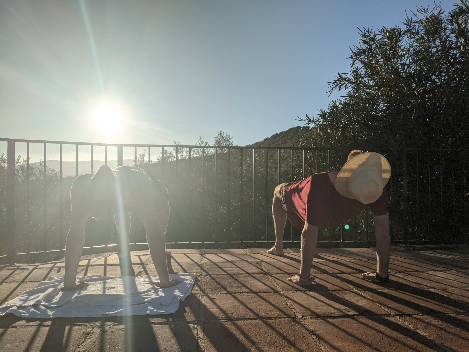 Two participants moving through a morning practice on a sunlit terrace