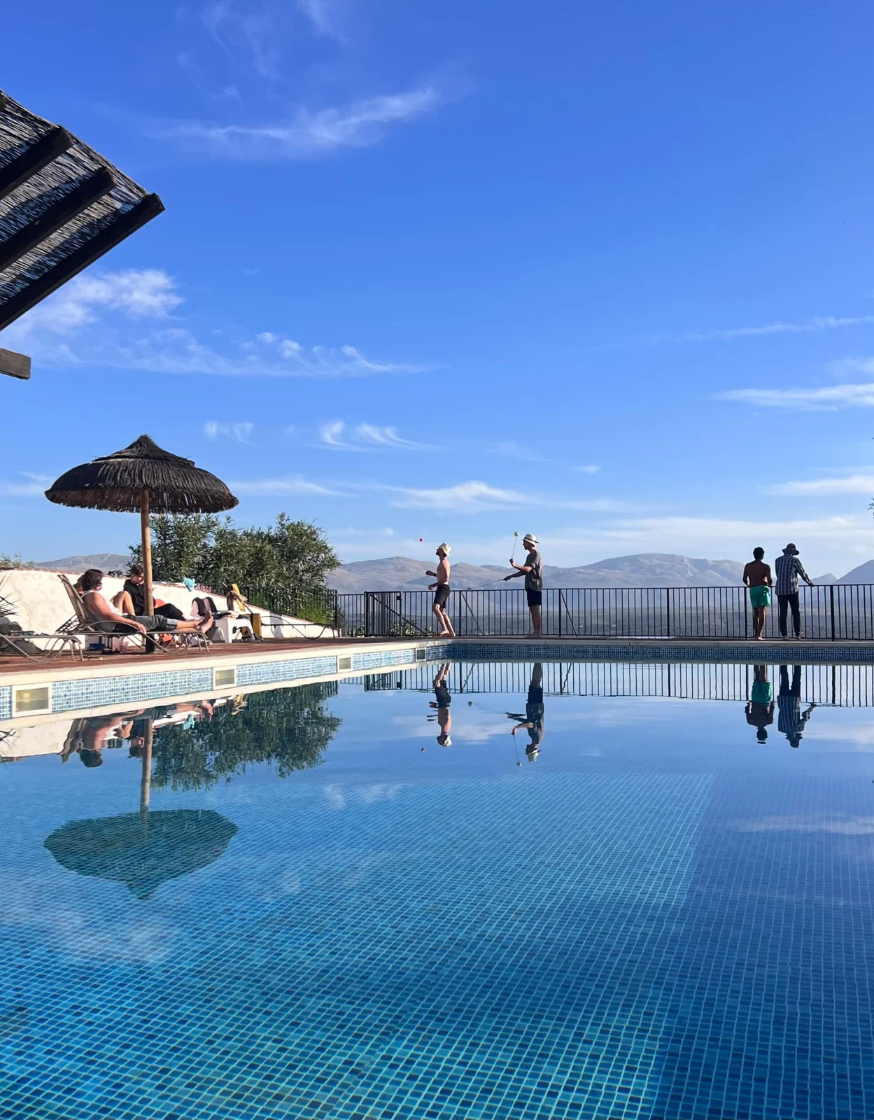 People beside the swimming pool with mountains reflected in the water