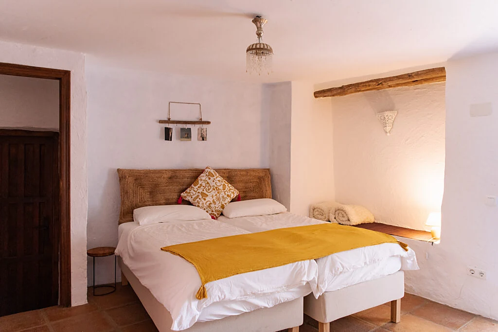 Twin bedroom with a mustard throw and a cosy lit alcove
