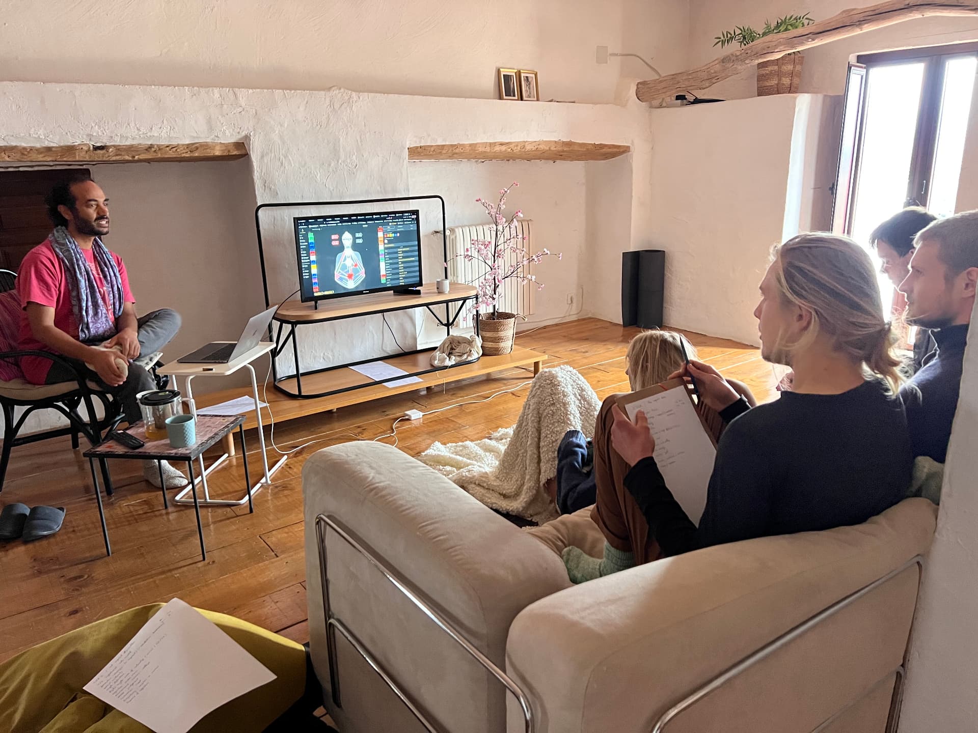 Shadi discussing a Human Design chart with participants in a shared living room